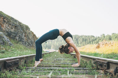 Young woman extreme climber stands on the bridge on railway tracks