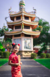 Portrait of smiling girl standing against built structure