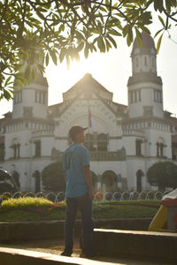 Rear view of man standing outside temple against building