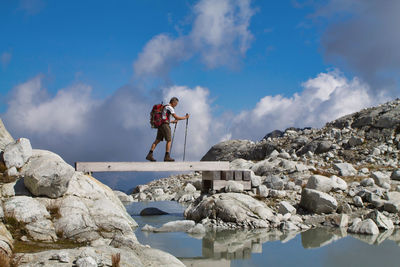 Man standing on rock against sky