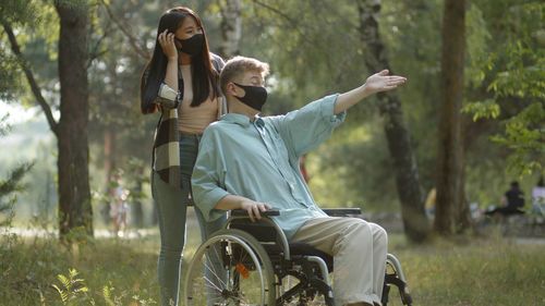 Young woman wearing mask with handicapped boyfriend at park