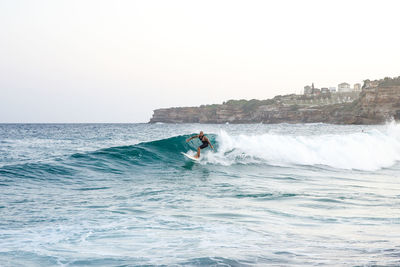 Man surfing in sea against clear sky