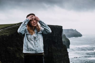 Woman standing by sea against sky