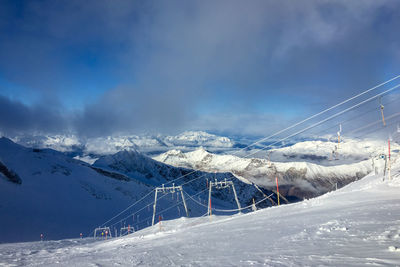 Snow covered mountain against sky with ski slope and lift