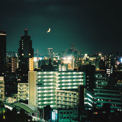 Illuminated buildings in city against sky at night