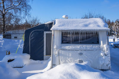 Campsite with a snowy and icy caravan in winter