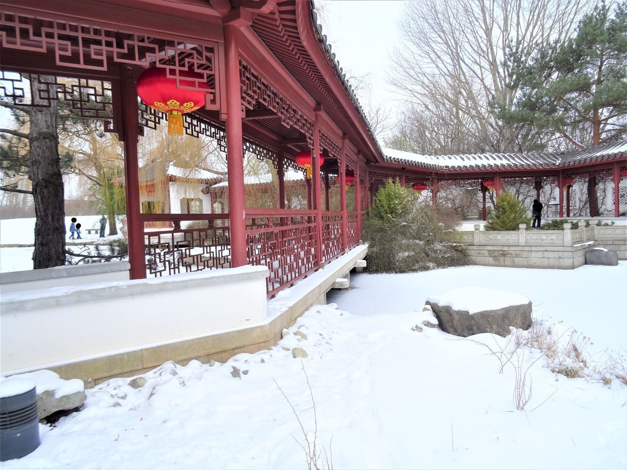 SNOW COVERED BRIDGE AMIDST TREES AND BUILDINGS