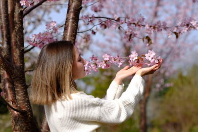 Rear view of woman standing by sakura tree