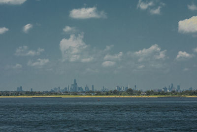 View of city by sea against cloudy sky