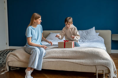 Curious kid son unwrapping gift box feeling excited getting present from caring loving mother