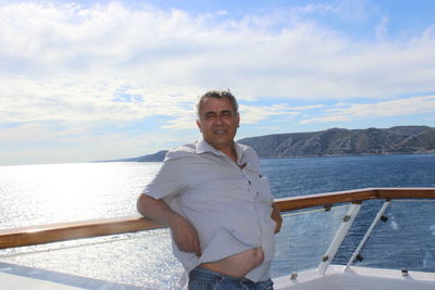 Mature man leaning on railing at boat over sea against sky