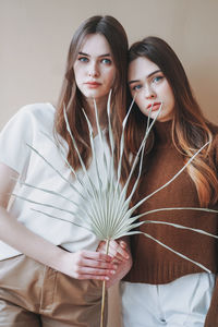 Portrait of beautiful females standing against beige background