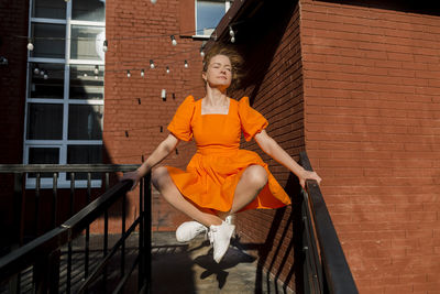 Woman with eyes closed balancing on railings of staircase