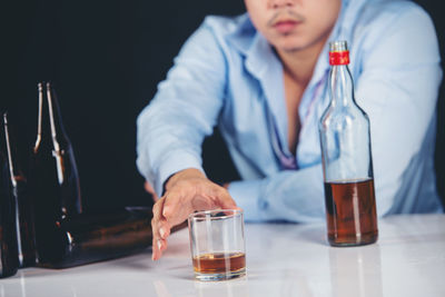 Midsection of man holding beer glass on table