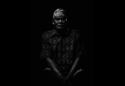 Portrait of young man sitting against black background