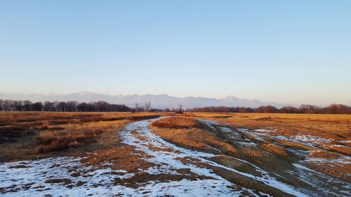 Snow covered field against clear sky during winter