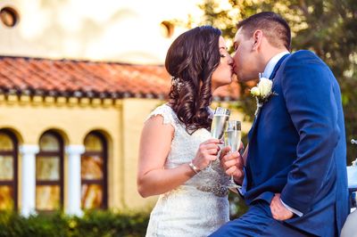 Bridal couple kissing while toasting champagne flutes