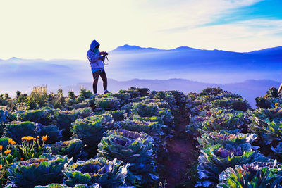 Rear view of man standing on mountain against sky