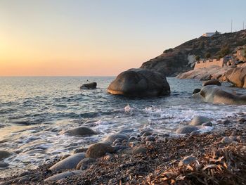 Rock formation on beach against sky during sunset