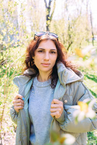 Portrait of young woman standing against plants