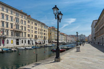 Boats in canal amidst buildings against sky