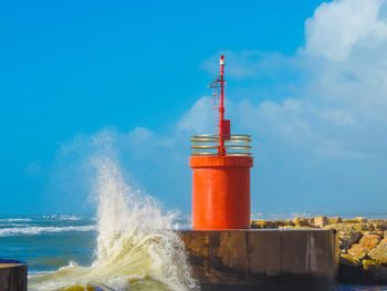 Lighthouse by sea against sky