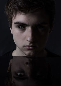 Close-up portrait of young man against black background