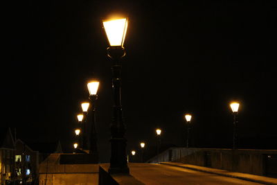 Illuminated street light against sky at night