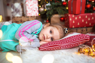 Portrait of cute girl lying down on christmas tree