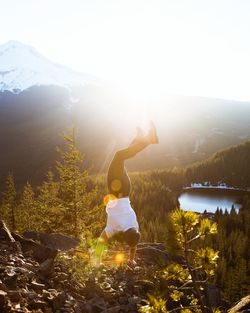 Rear view of woman on rock against landscape