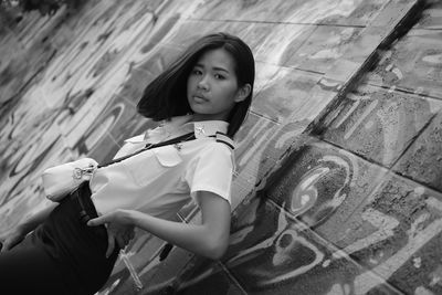 Portrait of young woman standing against wall