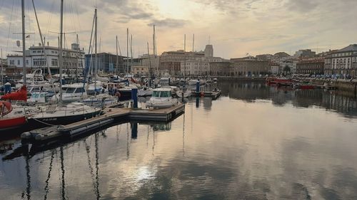 Sailboats moored at harbor against buildings in city