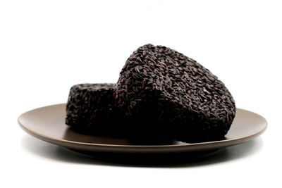 Close-up of chocolate cake in plate against white background