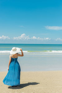 Woman in hat at beach against sky