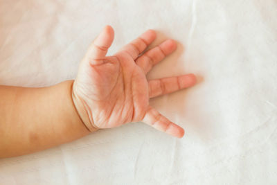 High angle view of baby hand on bed