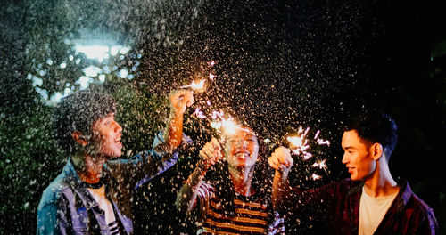 Friends holding illuminated sparklers outdoors at night