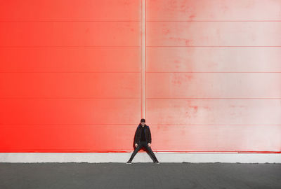 Full length of man standing against orange wall