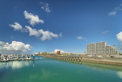 View of river and buildings against cloudy sky