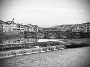 Bridge over river in city against sky