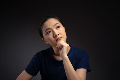 Portrait of beautiful young woman against black background