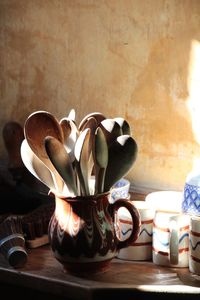 Wooden spoons in container on table by wall