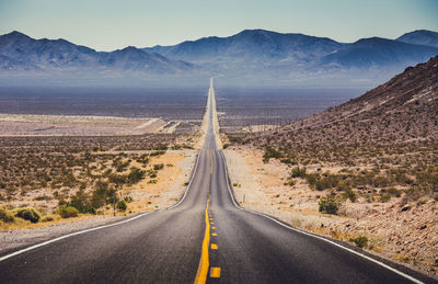 Road leading towards mountains against sky