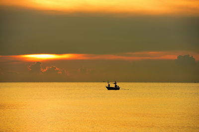 Silhouette sailboat in sea against sky during sunset