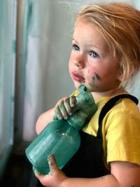 Close-up cute girl with bottle standing at home