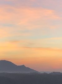 Scenic view of silhouette mountains against orange sky