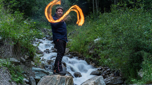 Full length of man standing by waterfall in forest