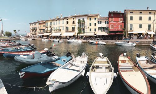 Boats moored at harbor against buildings in city