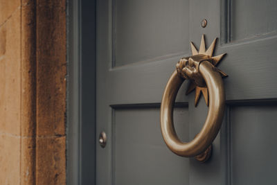 Close up of a metal door knocker on a wooden front door of a house.