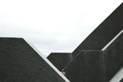 Woman standing amidst concrete structures against sky