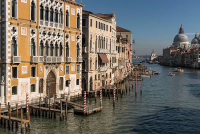 Boats in canal by buildings against sky